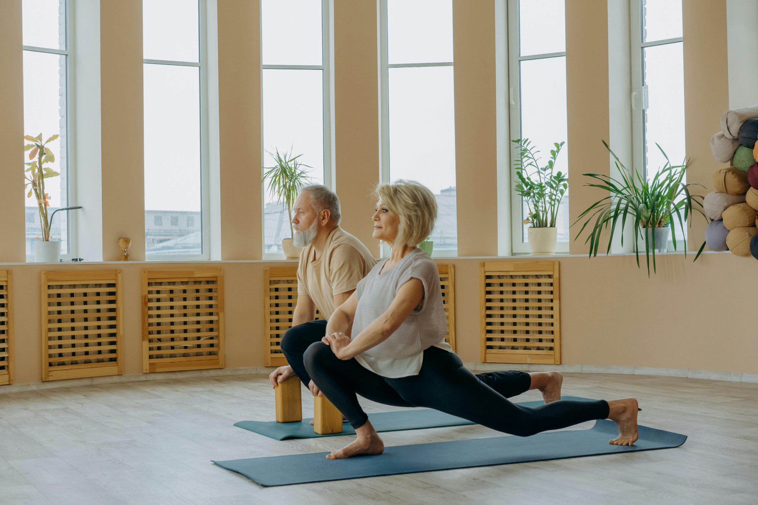 A senior couple practicing yoga indoors, focusing on a healthy lifestyle and flexibility.