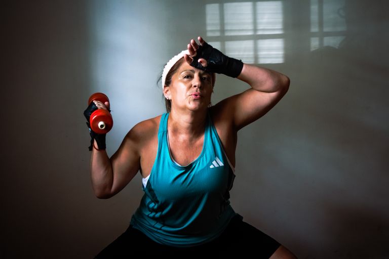 A determined woman working out at home with a dumbbell in focused exercise. Indoors motivational fitness.