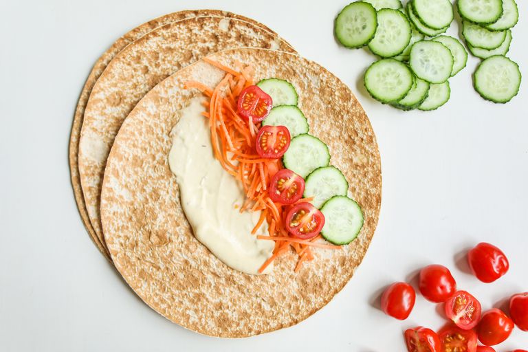 A healthy vegan wrap with fresh cucumbers, tomatoes, and carrots on whole wheat pita.