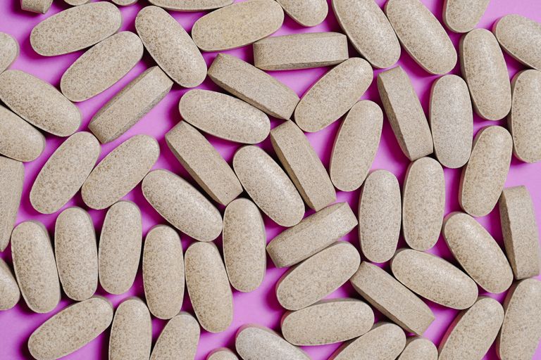 Brown oblong tablets scattered on a bright pink background, highlighting healthcare themes.