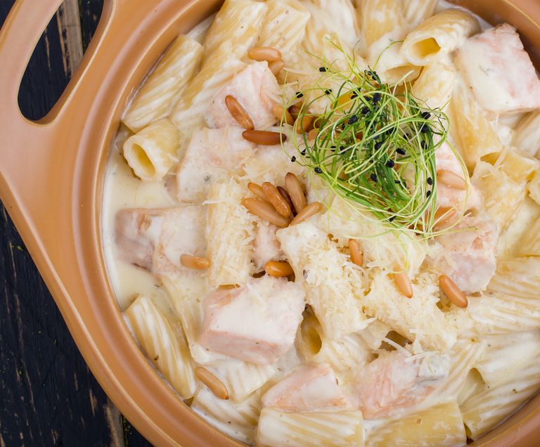 Delicious creamy rigatoni with salmon, garnished with sprouts and pine nuts for a flavorful meal.