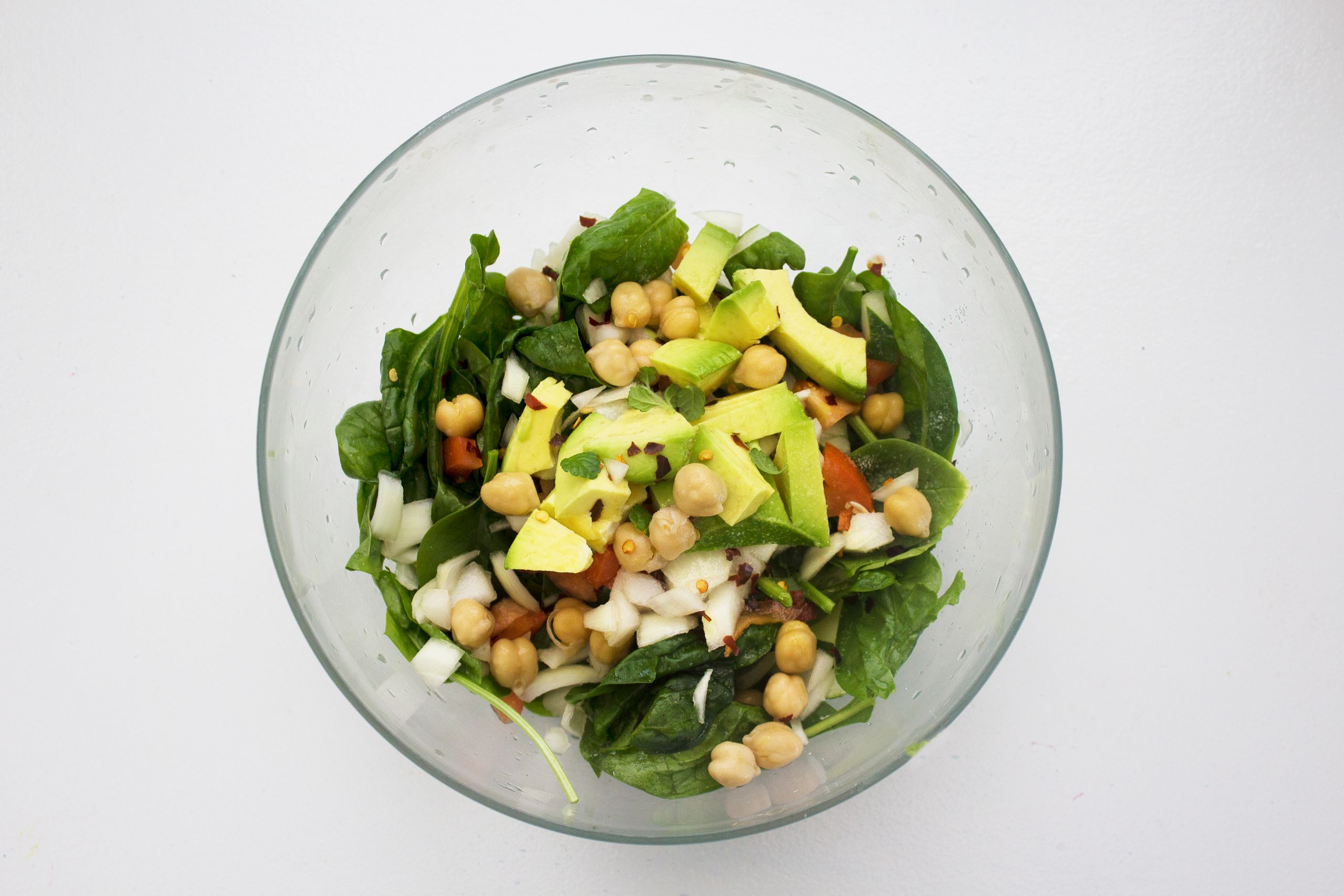 Fresh spinach salad featuring avocado and chickpeas, perfect for healthy eating.