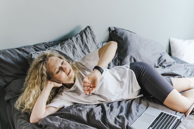Woman reclining on bed using a laptop, enjoying a relaxing moment indoors.
