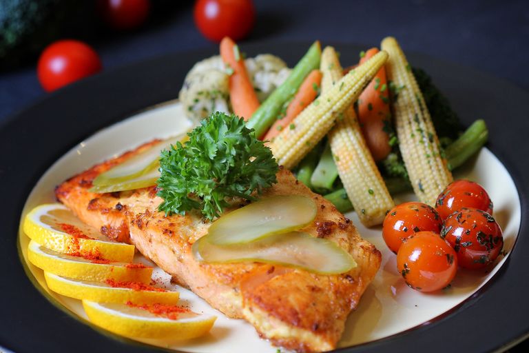 A beautifully plated salmon dish with fresh vegetables and lemon slices, perfect for a gourmet meal.