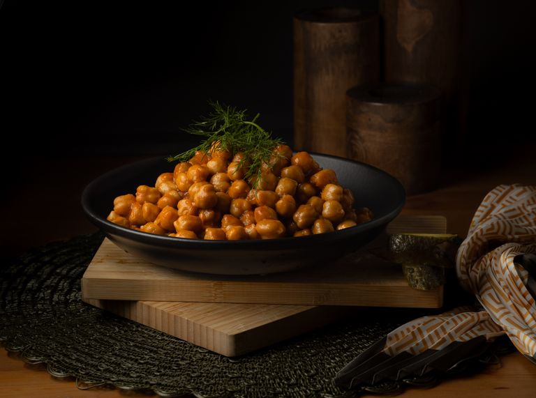 A bowl of spiced chickpeas garnished with fresh herbs, perfect for a healthy meal.
