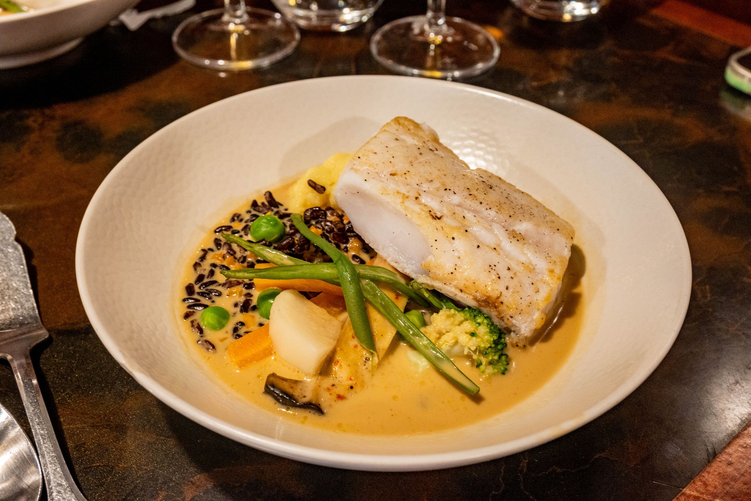 A delicious gourmet seafood dish featuring cod, vegetables, and creamy sauce.