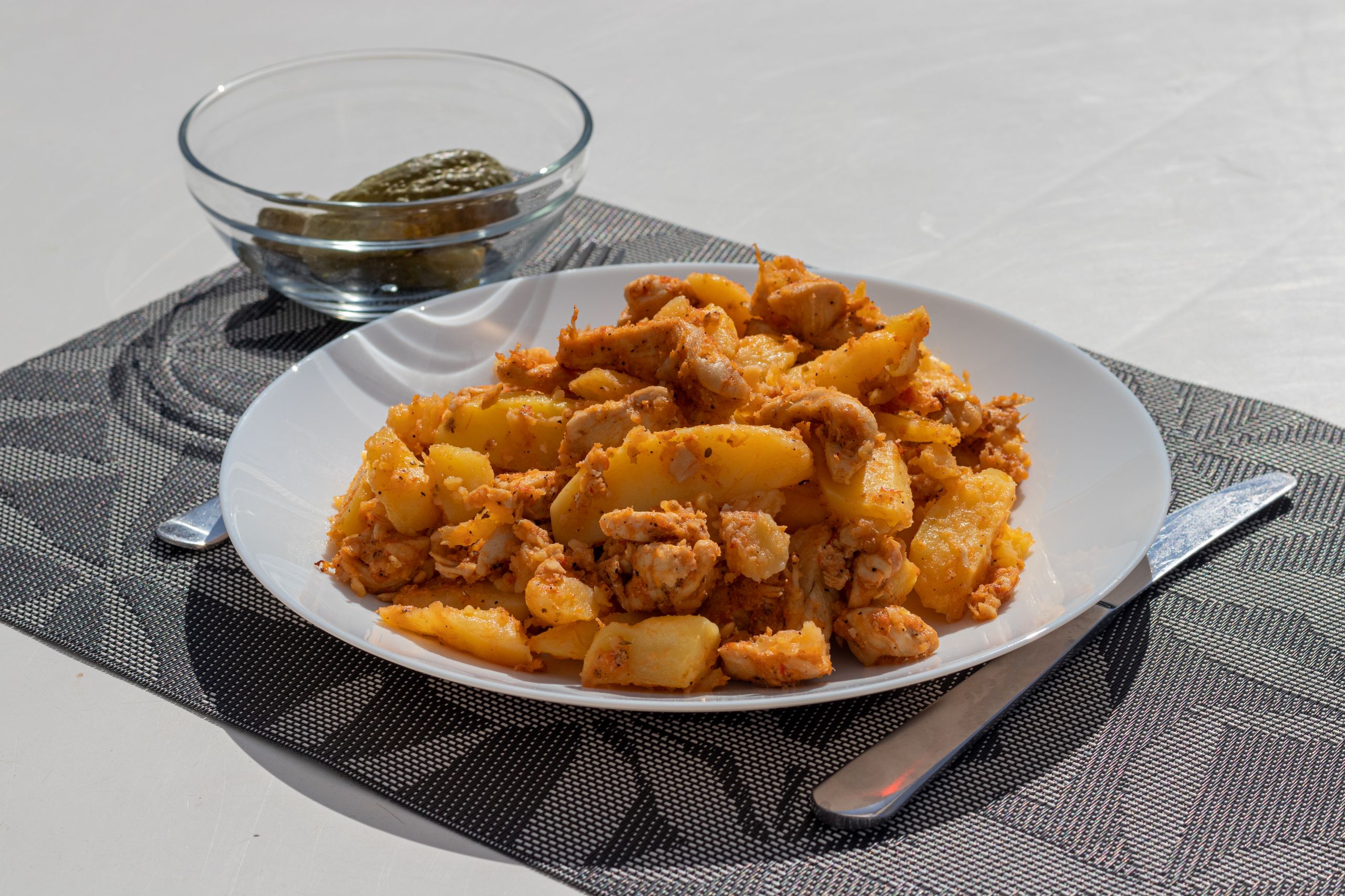 A delicious plate of chicken and potatoes served with pickles on an outdoor table in Szántód.