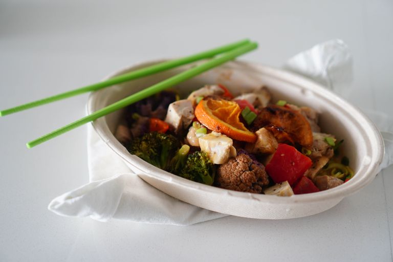 A vibrant Asian stir-fry with tofu, vegetables, and citrus in a white bowl.