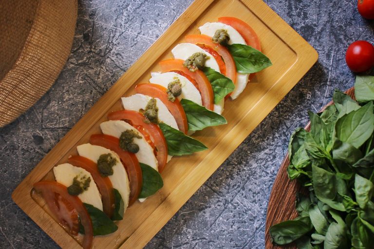 Appetizing Caprese salad with mozzarella, tomatoes, and basil on a wooden board.