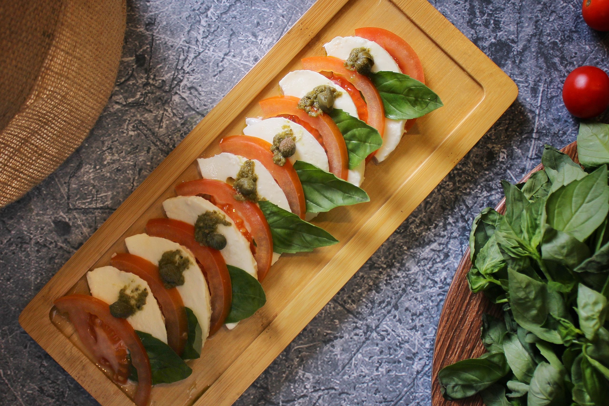 Appetizing Caprese salad with mozzarella, tomatoes, and basil on a wooden board.