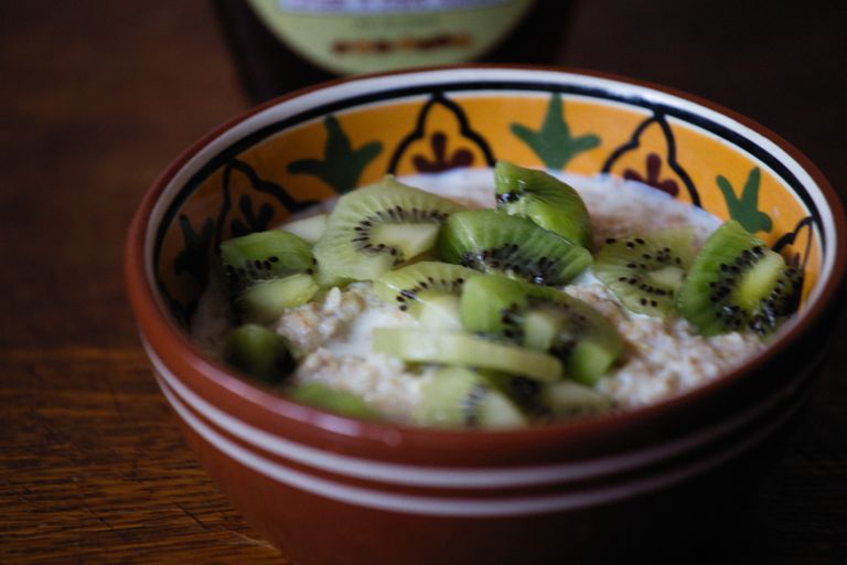 Close-up of sliced kiwi over oatmeal in a colorful ceramic bowl, perfect for a healthy breakfast.