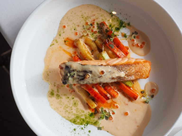 Delicious gourmet salmon fillet on a bed of glazed vegetables with creamy sauce, perfect overhead shot.