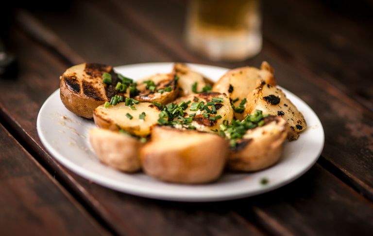 Delicious grilled potatoes garnished with fresh chives, perfect for a rustic meal.