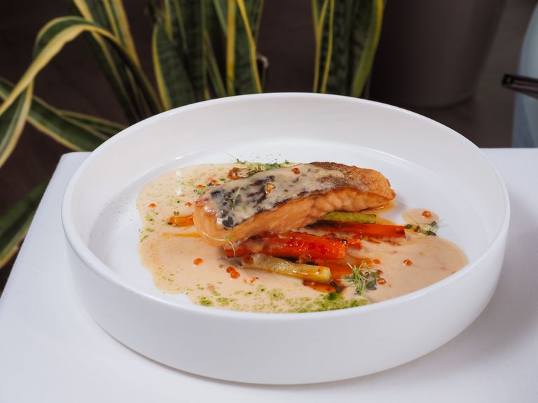 Delicious grilled salmon served with mixed vegetables and creamy sauce in a modern setting.