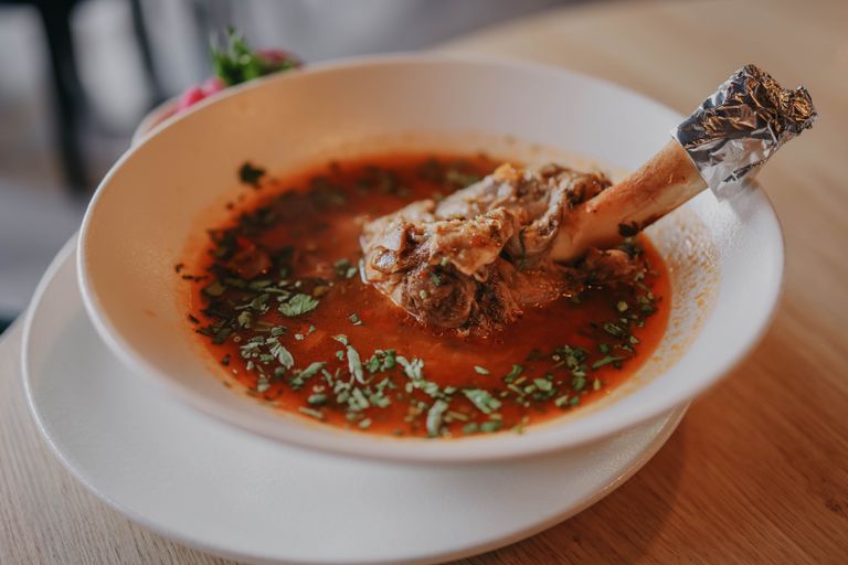 Delicious lamb shank soup garnished with fresh herbs, perfect for a cozy meal.
