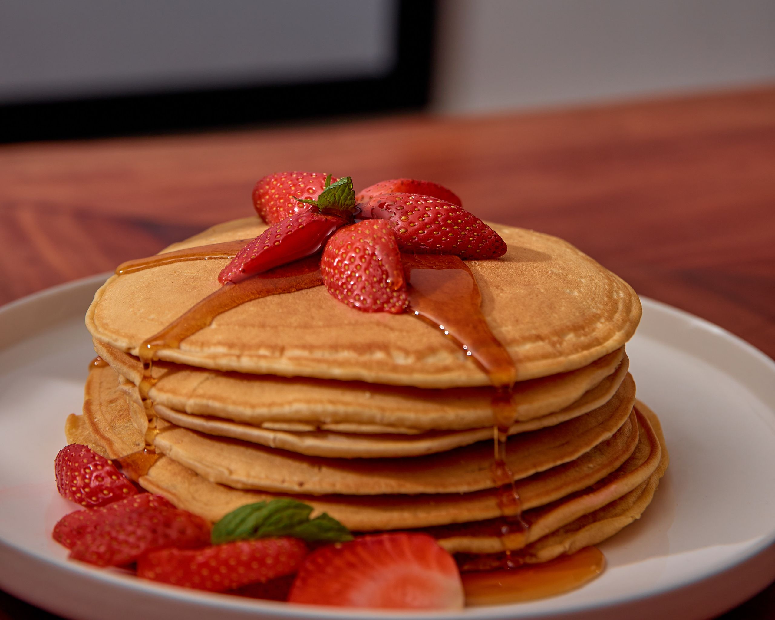Delicious pancakes topped with fresh strawberries and syrup, perfect breakfast treat.