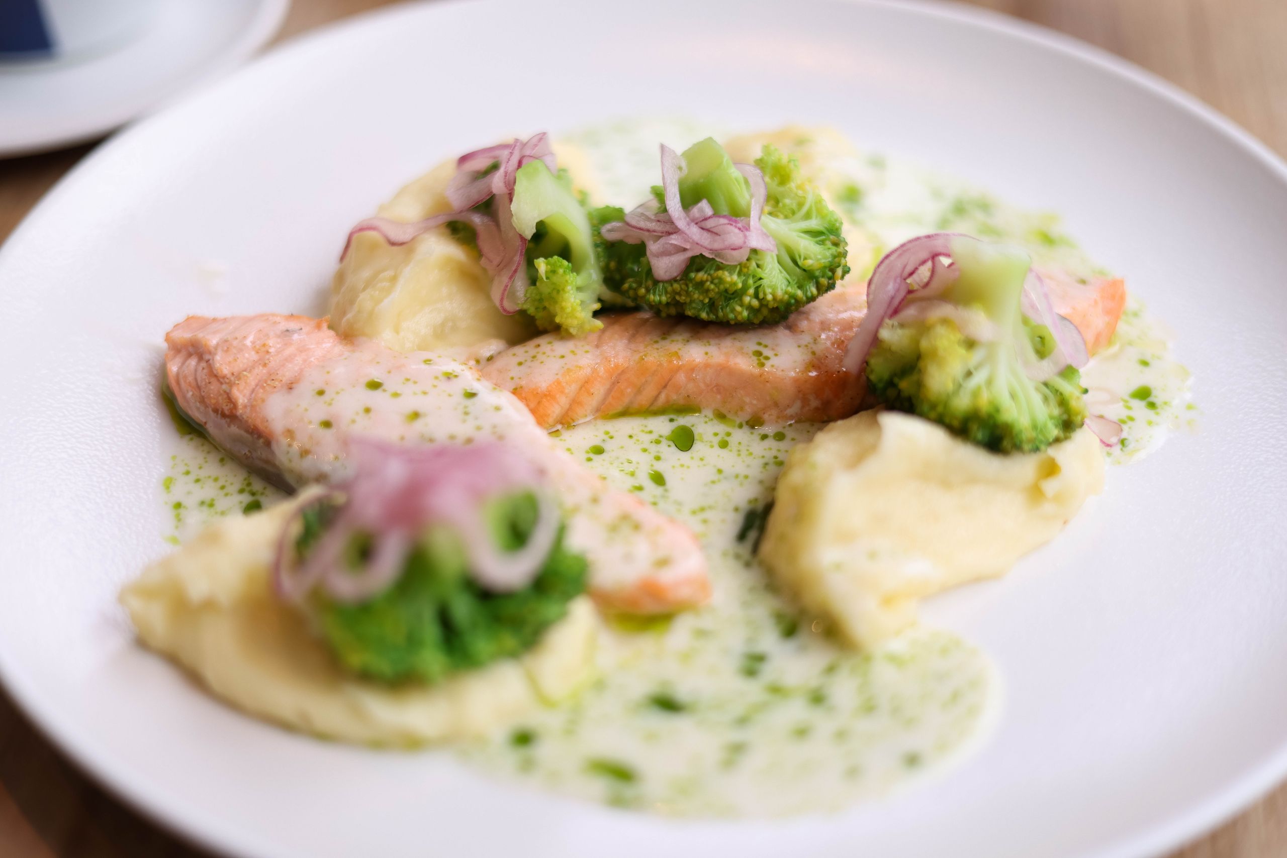 Delicious salmon served with broccoli, mashed potatoes, and creamy sauce.