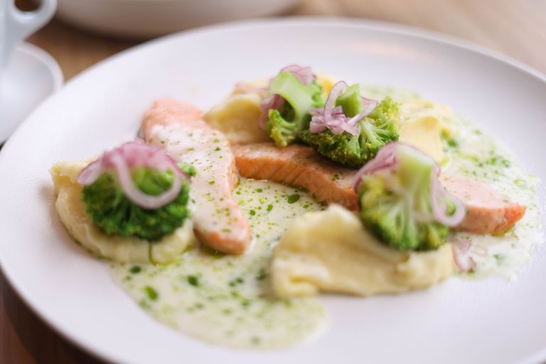 Delicious salmon served with mashed potatoes, broccoli, and a creamy herb sauce.