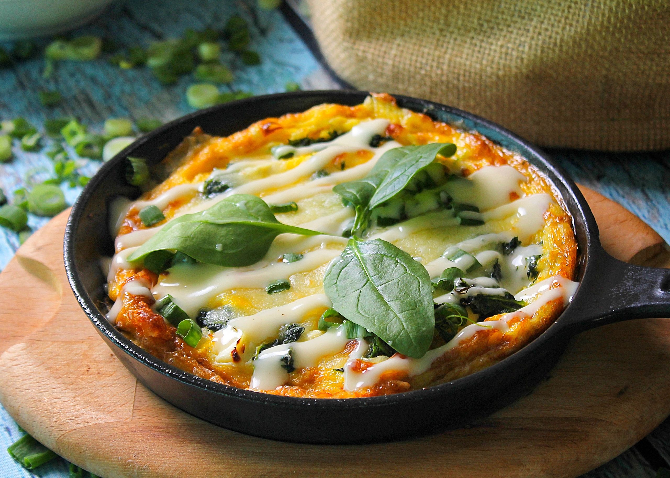 Delicious scrambled eggs with fresh spinach and cheese in a skillet. Perfect for brunch.