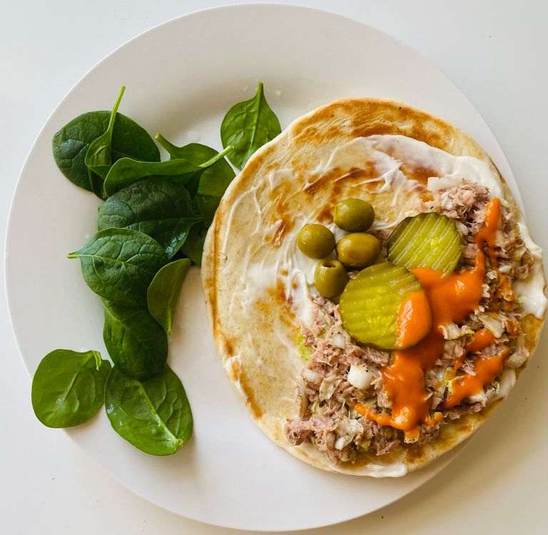Delicious tuna wrap with pickles and a side of spinach, perfect for a tasty meal.