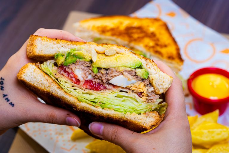 Delicious veggie sandwich with avocado and chips, perfect for lunch or snack.
