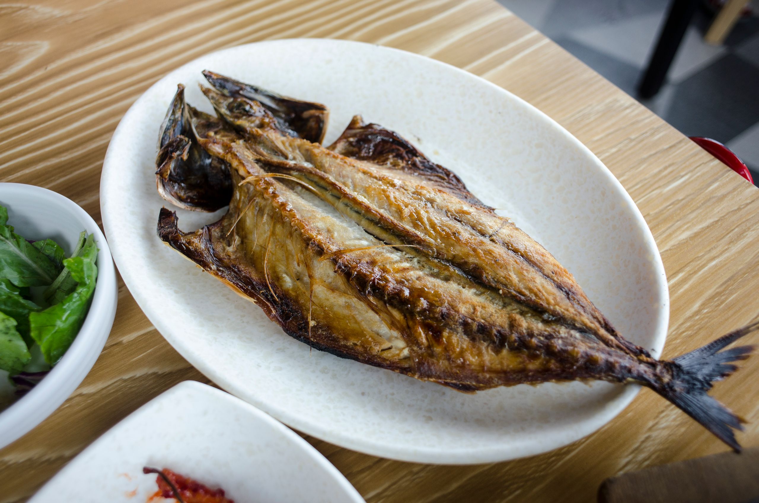Deliciously crispy fried fish served on a white plate, accompanied by fresh greens. Perfect for seafood lovers.