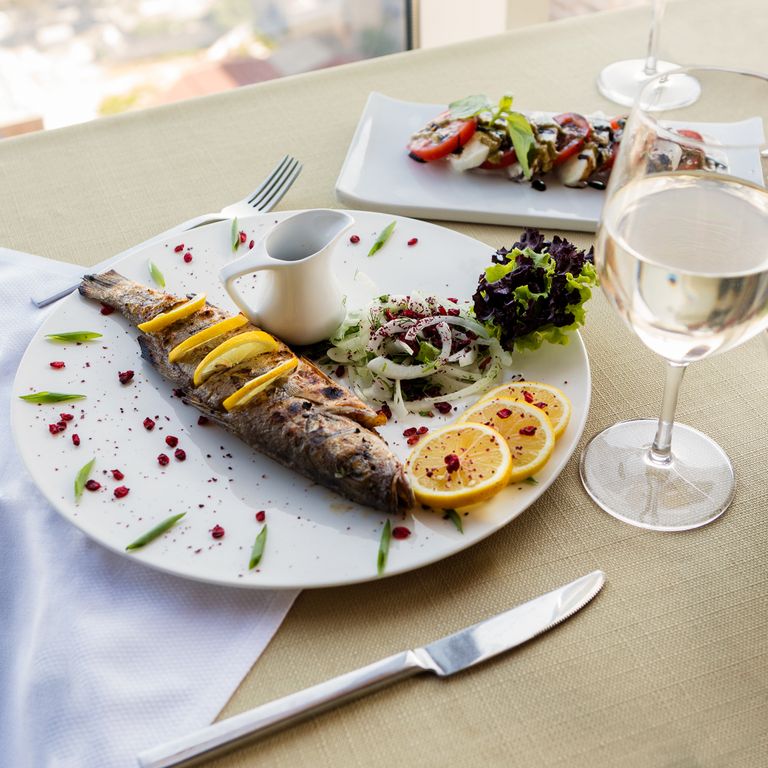 Deliciously presented whole fish with lemon slices, ideal for fine dining settings.