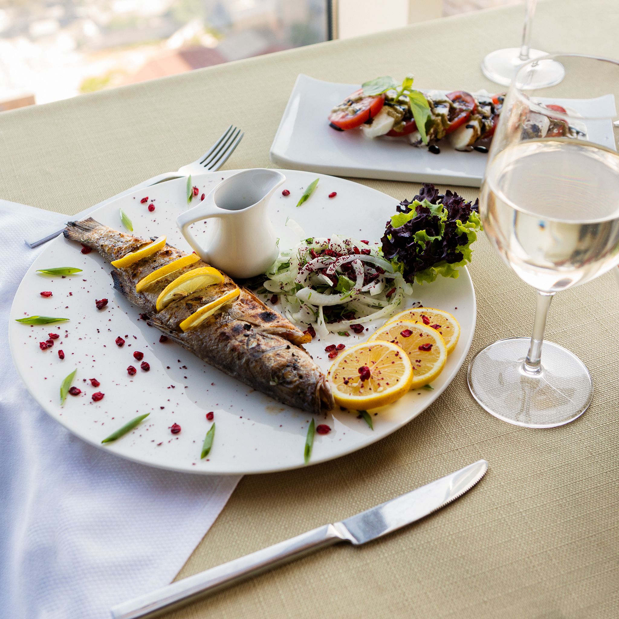 Deliciously presented whole fish with lemon slices, ideal for fine dining settings.