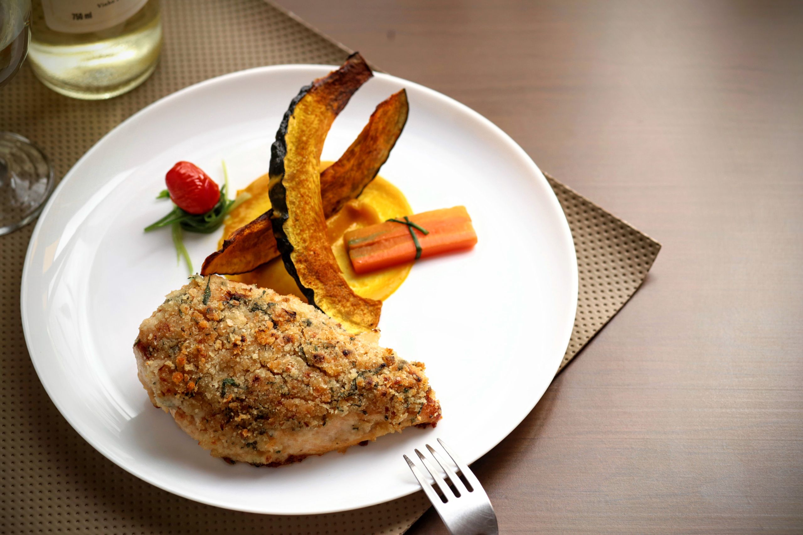 Elegant plated chicken dish with roasted vegetables and wine, perfect for gourmet dining.