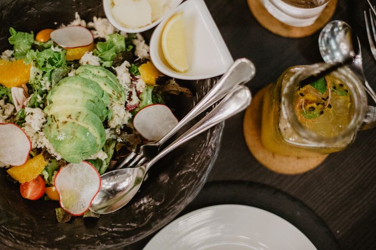 From above of fruit and vegetable salad served in glass bowl and yellow fruit smoothie on wooden table