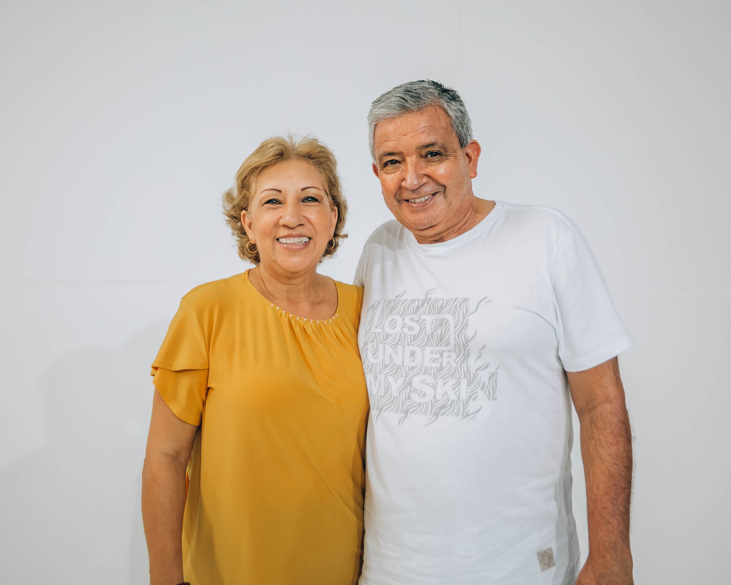 Happy elderly couple smiling in a portrait with a white background.
