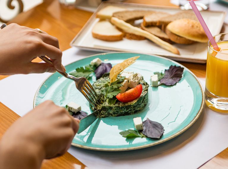 Plate of spinach omelette with feta, served with bread and orange juice. Perfect for a nutritious breakfast.