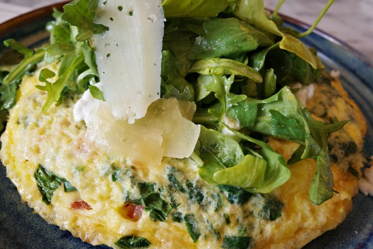 Savor a healthy omelette topped with fresh arugula and shaved cheese, perfect for a gourmet breakfast.