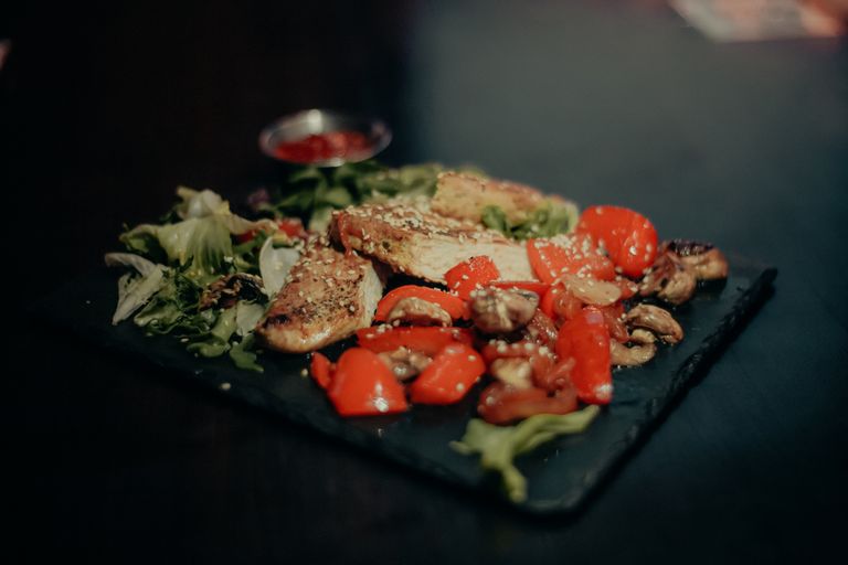 Savor a savory dish of grilled chicken with vibrant peppers, mushrooms, and greens.