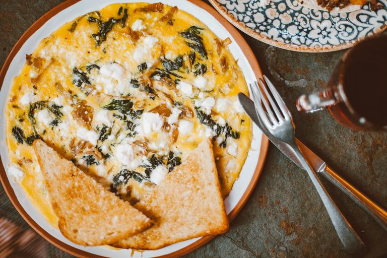 Savory omelette with vegetables, cheese, and toasted bread on a plate.