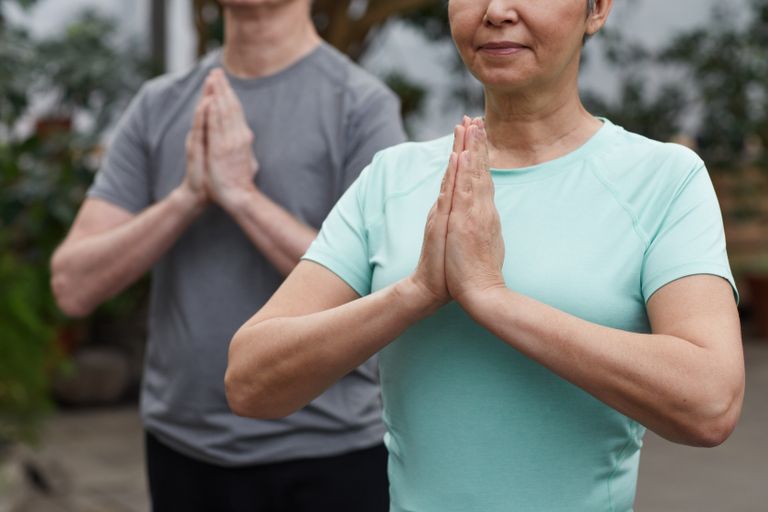 Senior couple in a meditative yoga pose outdoors, promoting wellness and a healthy lifestyle.