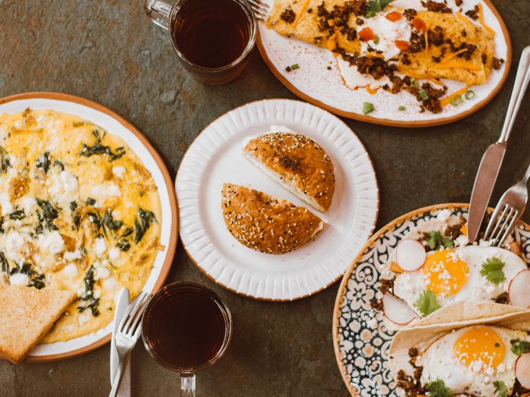 Top view of a brunch table with omelettes, bread, and coffee served on a wooden table.