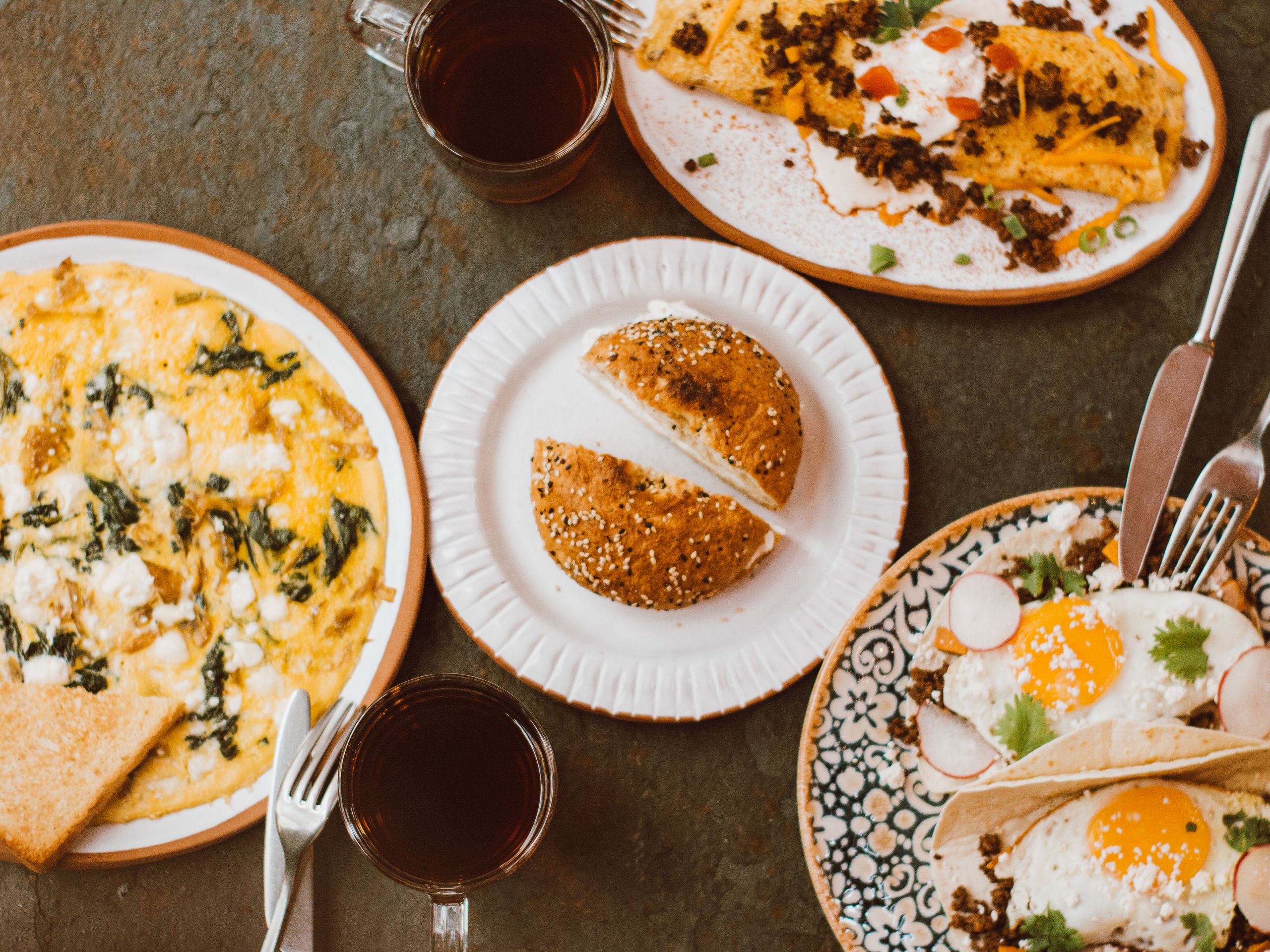 Top view of a brunch table with omelettes, bread, and coffee served on a wooden table.