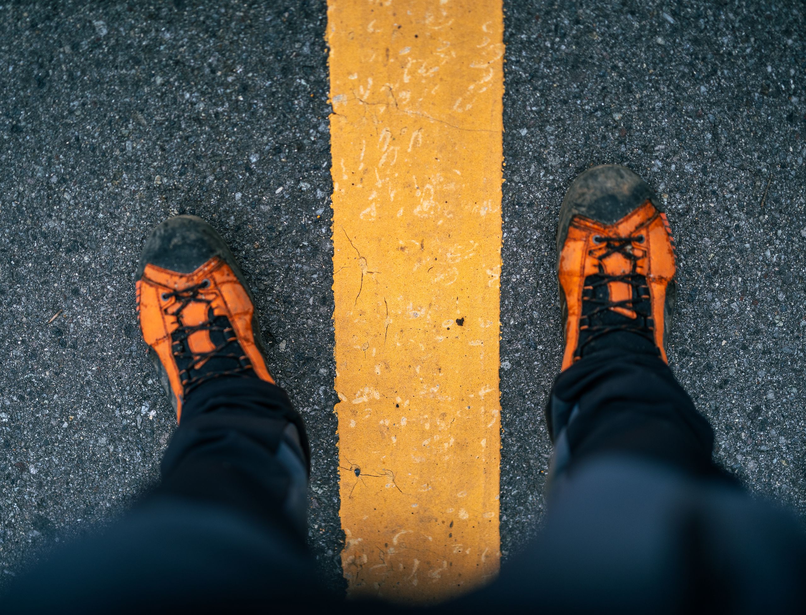 Vibrant orange hiking shoes on a lined road in Nikko, Japan, symbolizing adventure.