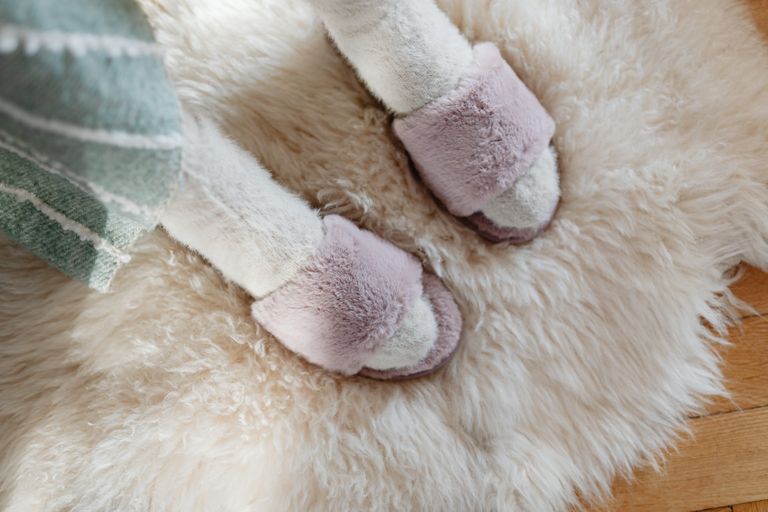 Close-up of fuzzy slippers on a comfy rug, evoking warmth and coziness.