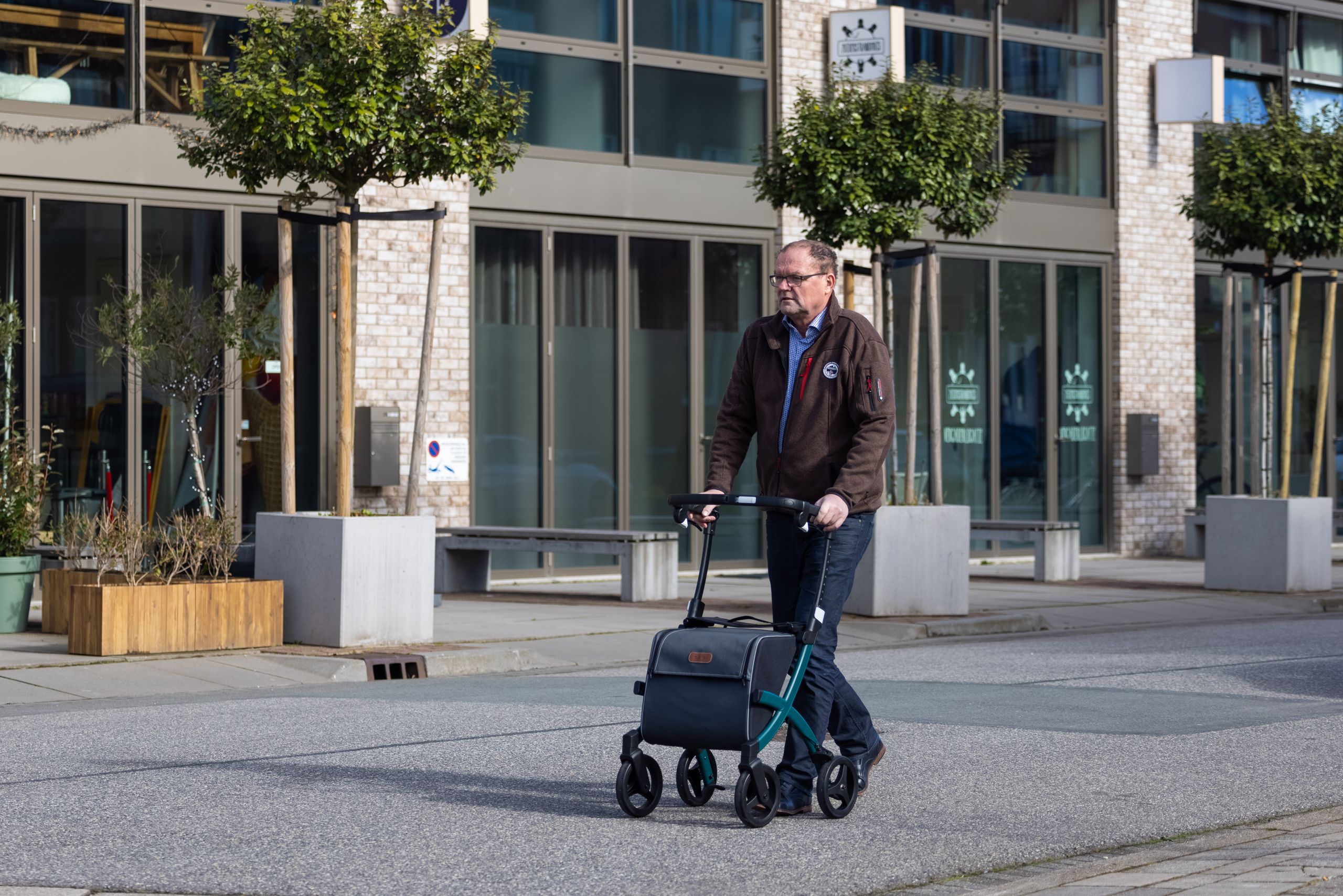 Senior man using a rollator while walking on a city street, showcasing urban mobility.